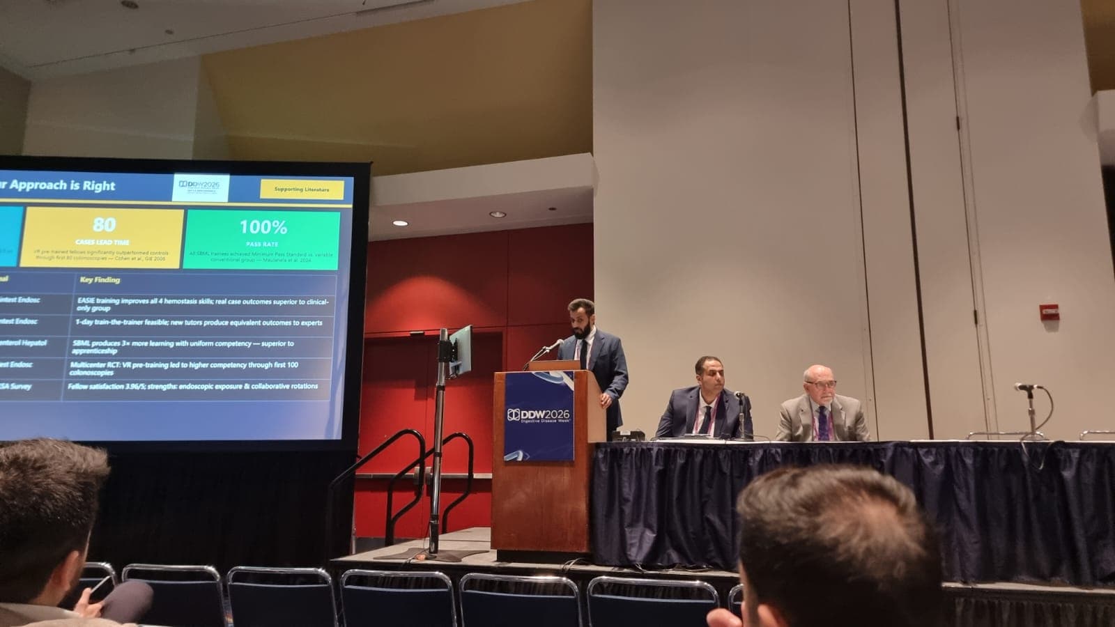 A panellist addressing the audience while colleagues listen during the SGA × ASGE clinical session at DDW 2026.