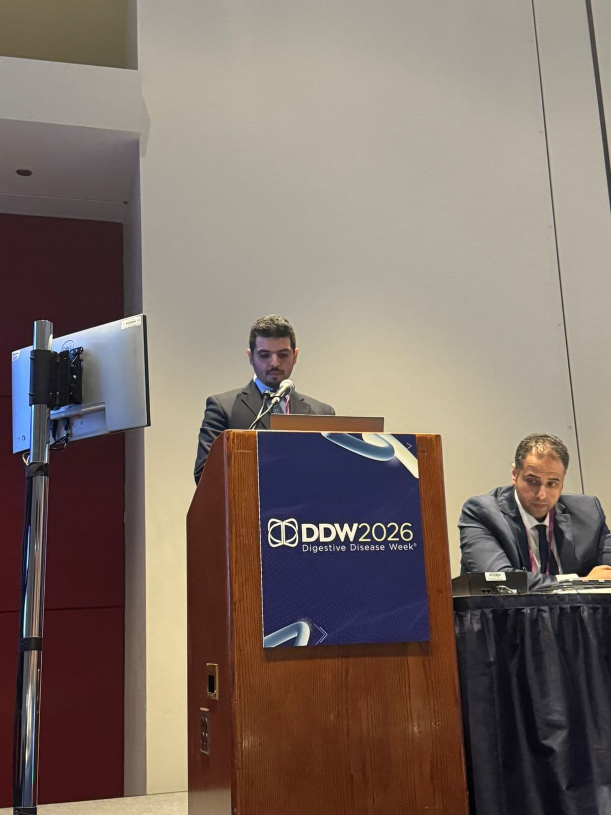 Speaker delivering remarks at the DDW 2026 podium during the SGA × ASGE clinical session.